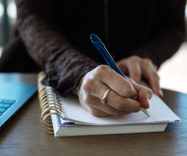 vrouw schrijft in een schrift tijdens reflectie op moederschap en onvervulde kinderwens